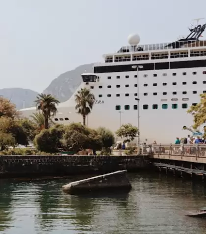 Un gran crucero atracado en un pintoresco puerto rodeado de palmeras y monta�as.