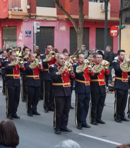 Procesi�n de la Semana Santa Marinera recorriendo una calle de Valencia con casas coloridas y p�blico observando.