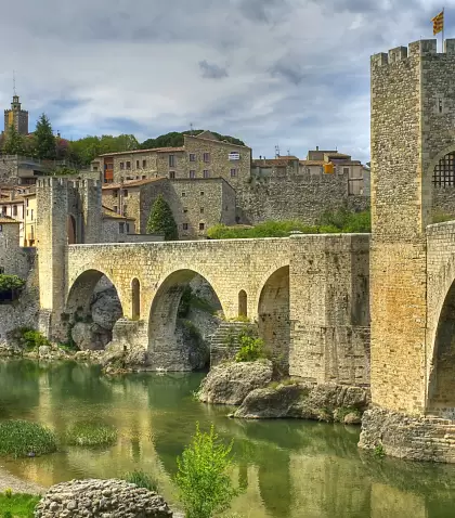 Pueblo de Besal� en abril con puente medieval y paisaje verde.