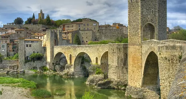 Pueblo de Besal� en abril con puente medieval y paisaje verde.