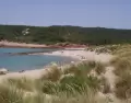 Cala de Menorca en julio con agua turquesa y arena clara.
