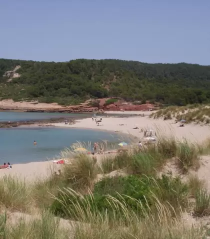 Cala de Menorca en julio con agua turquesa y arena clara.